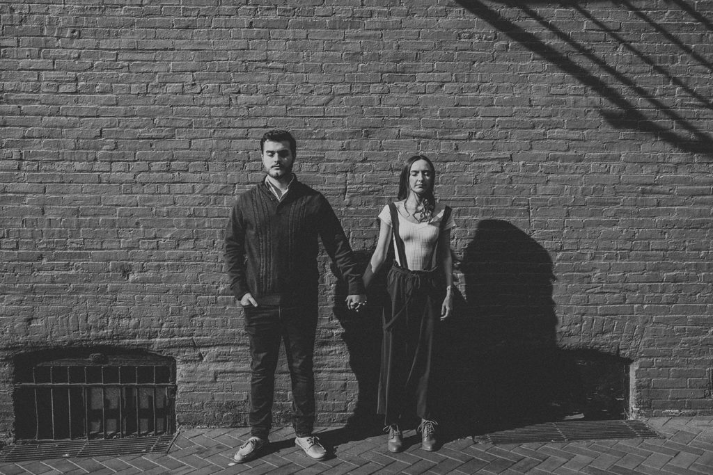 Couple standing beside one another with eyes shut outside of Lancaster Central Market in Downtown Lancaster, PA