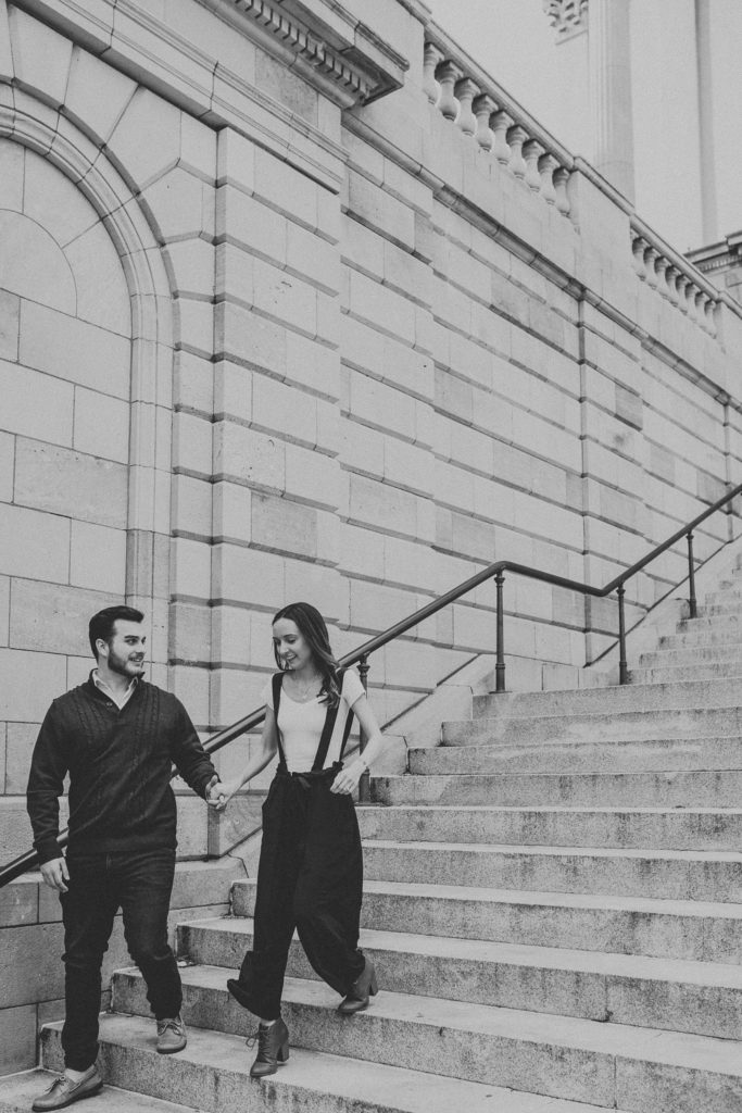 Engaged couple walking down the steps hand in hand on the steps of the Lancaster County Courthouse in Downtown Lancaster, PA