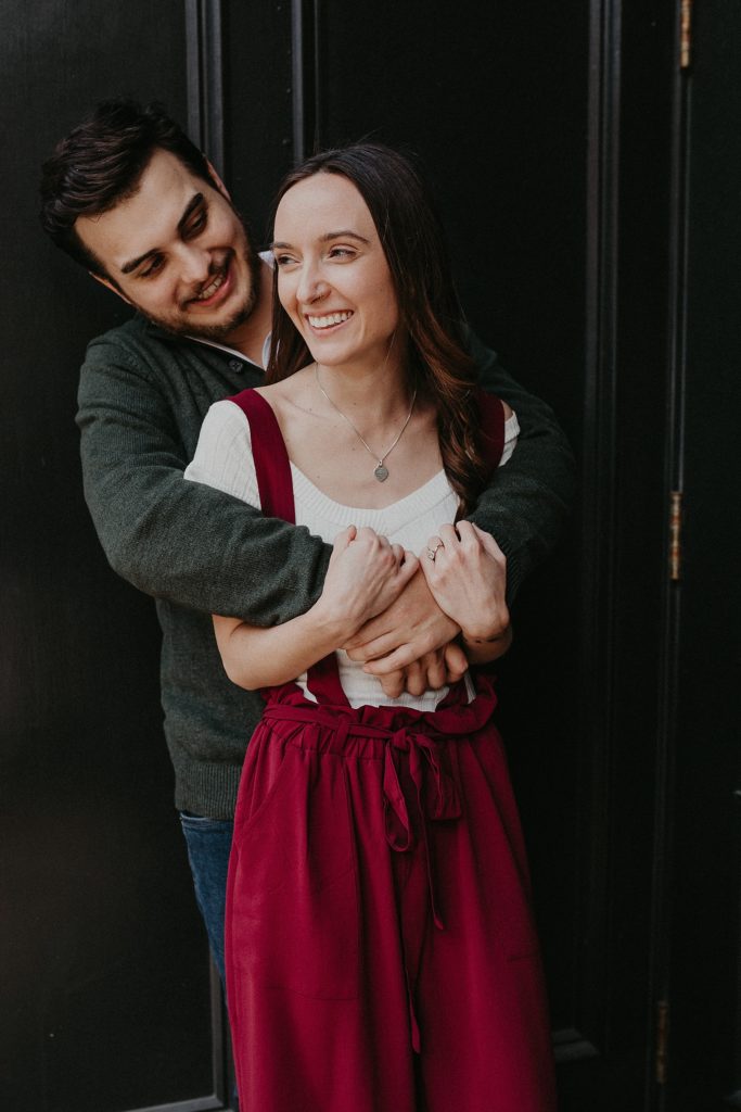 Engaged couple holding each other in a hug as they laugh and share candid moments outside of Excelsior in Downtown Lancaster, PA