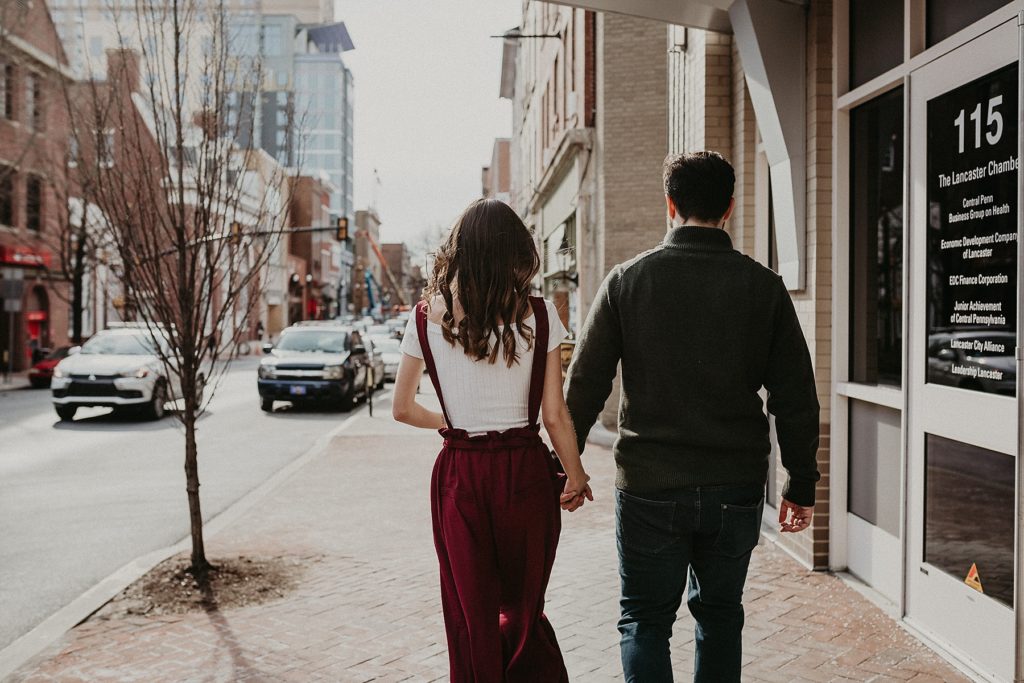 Candid capture of couple walking down the street during their engagement session in Downtown Lancaster, PA
