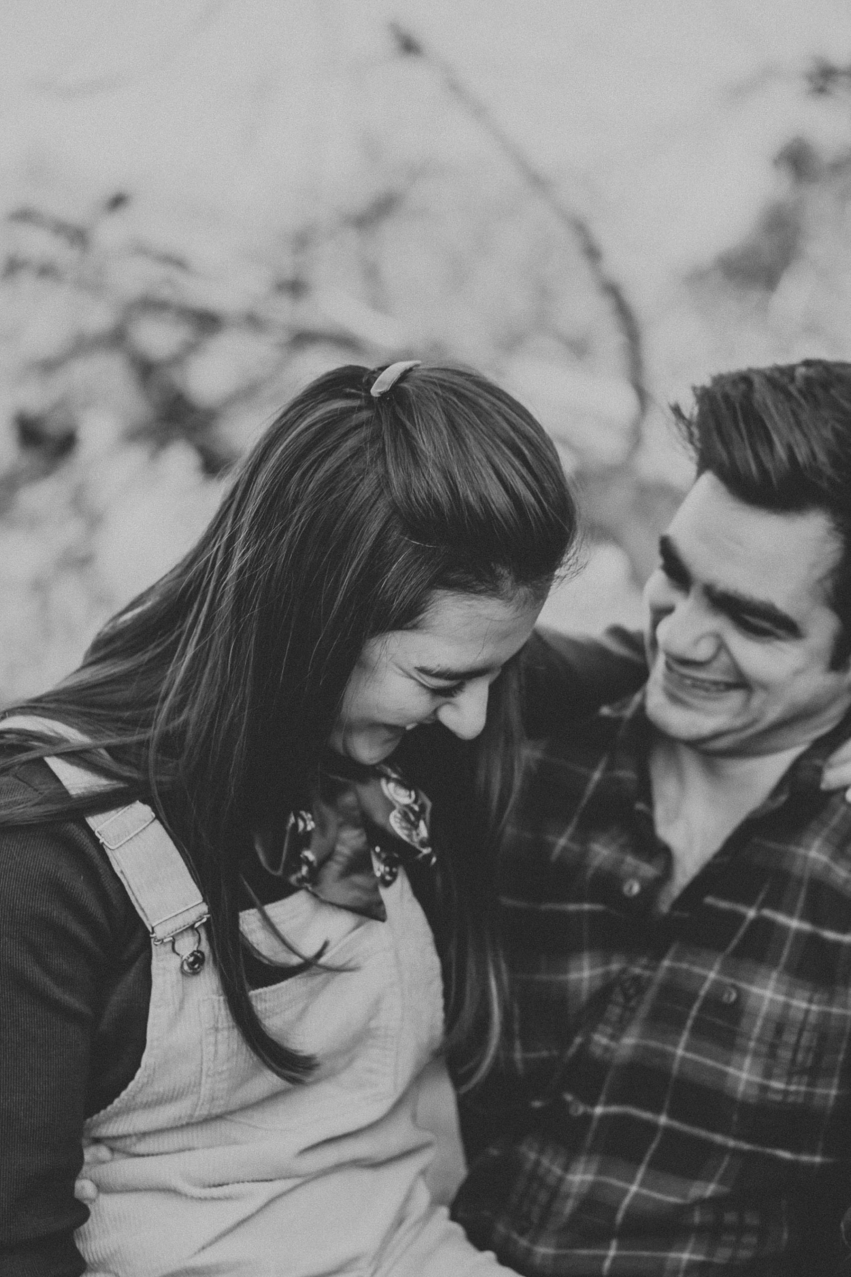 Girl sitting in guys lap with her arms wrapped around his neck as they laugh together