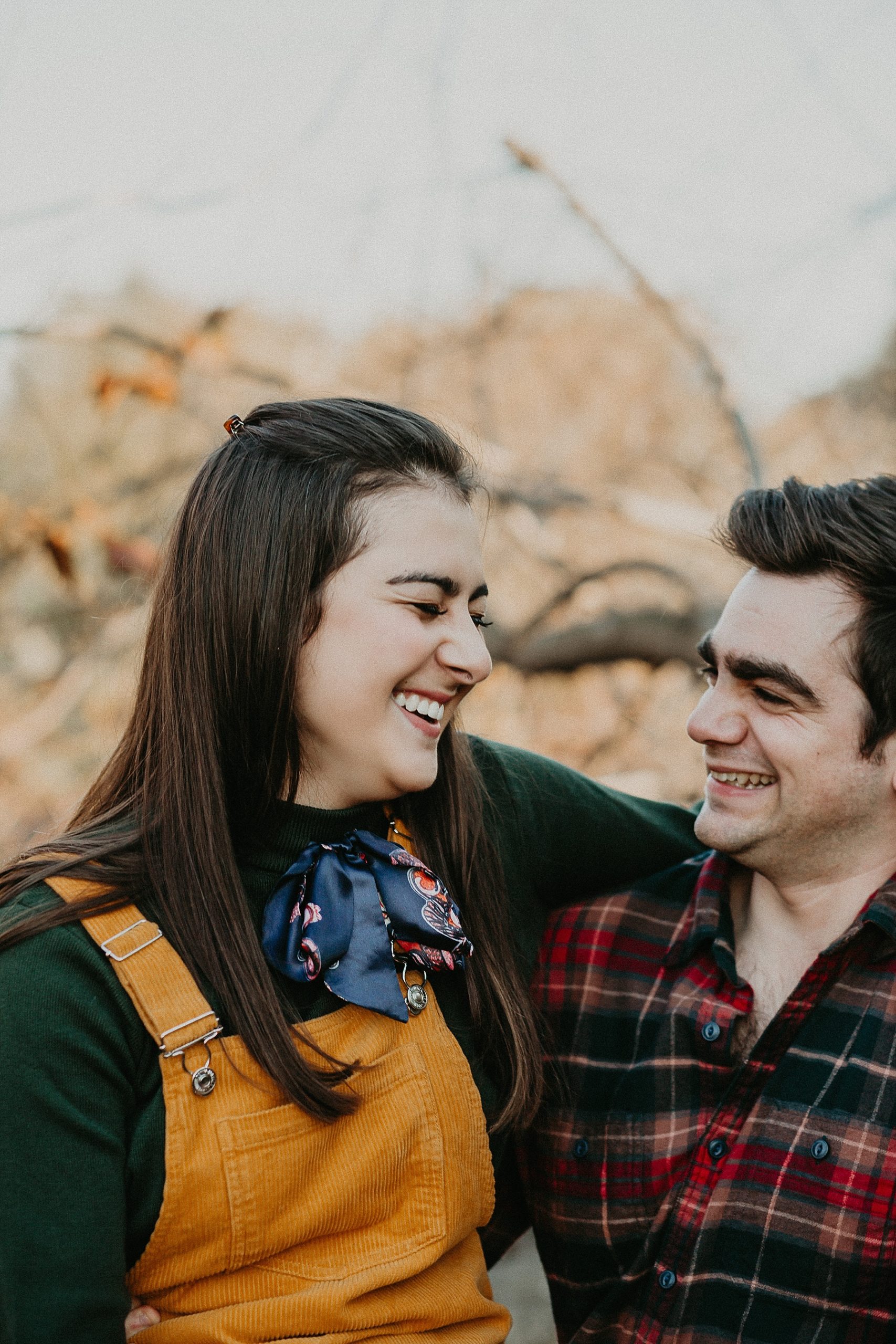 Girl sitting in guys lap with her arms wrapped around his neck as they laugh together