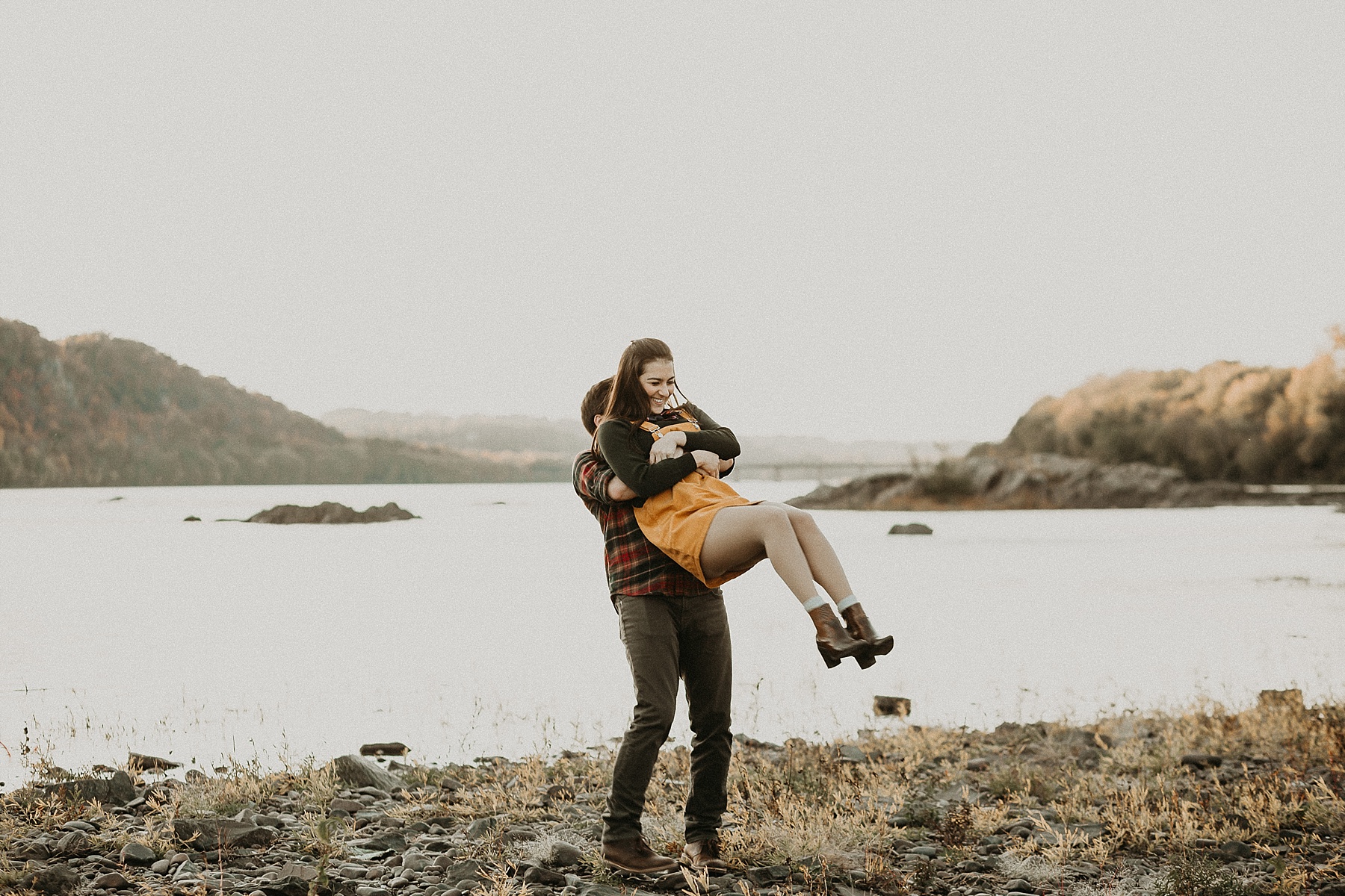 Guy behind girl with his arms wrapped around her as he picks her up and swings her around as she laughs