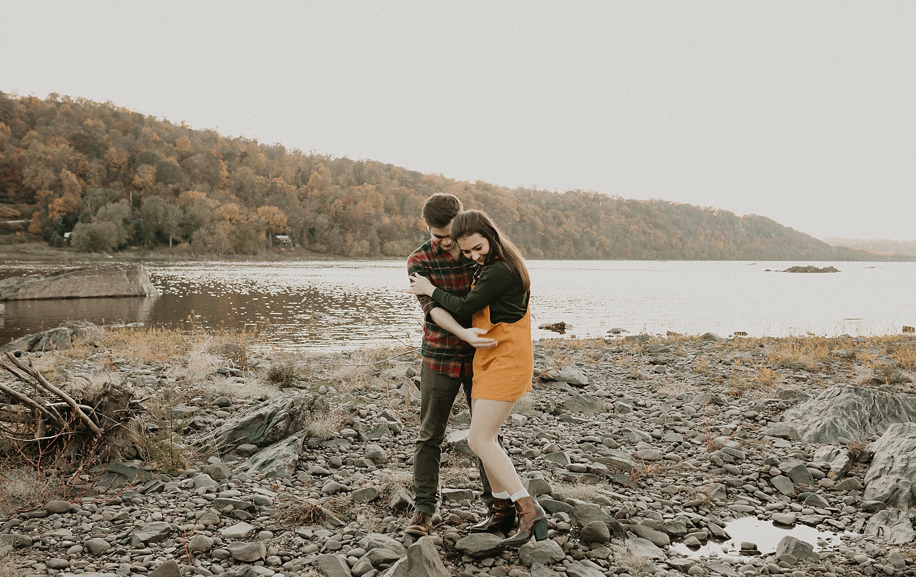 Engaged couple holding hands as they walk playfully along the Susquehanna River laughing and having fun