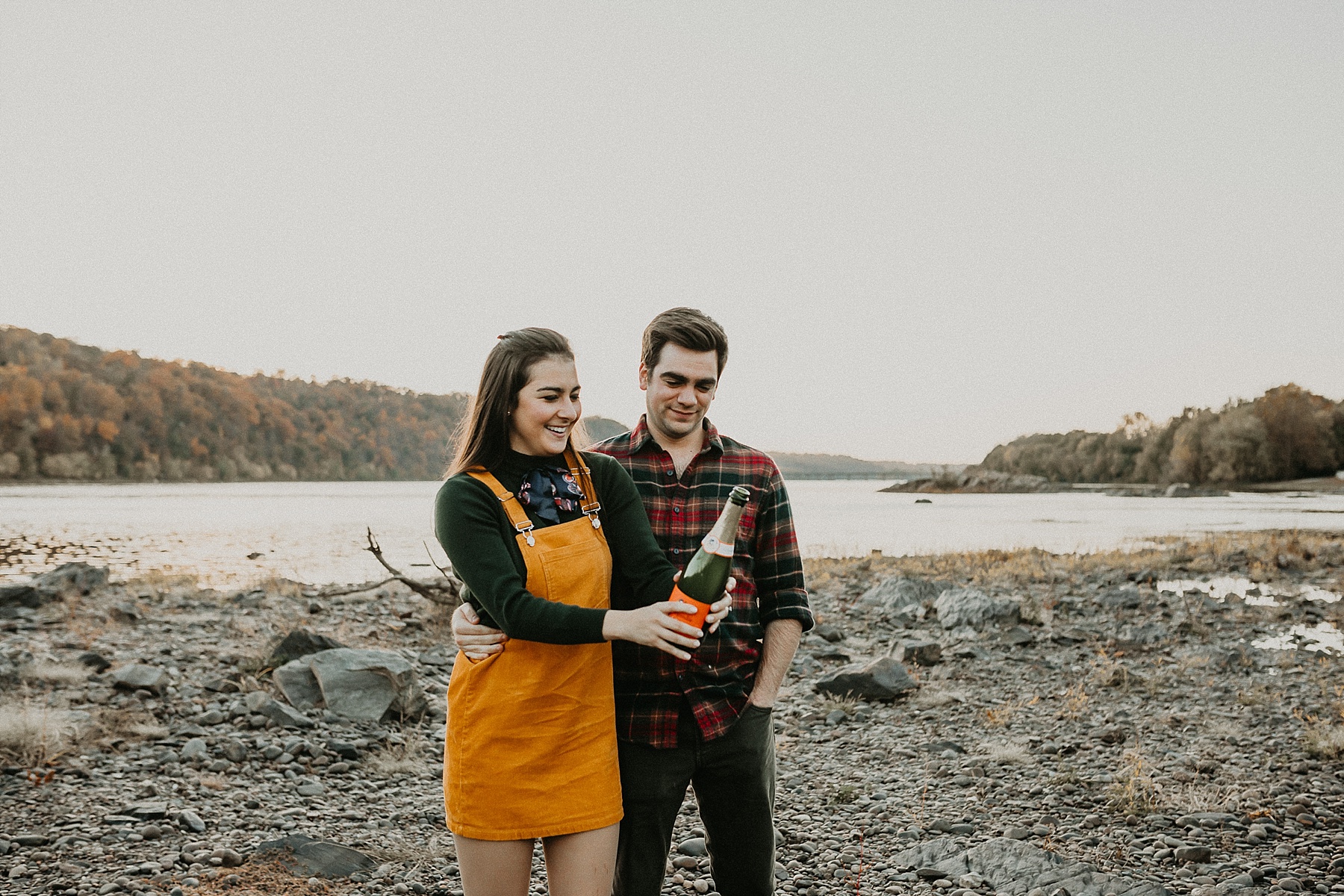 Shaking and popping champagne as it sprays all over laughing couple during engagement session