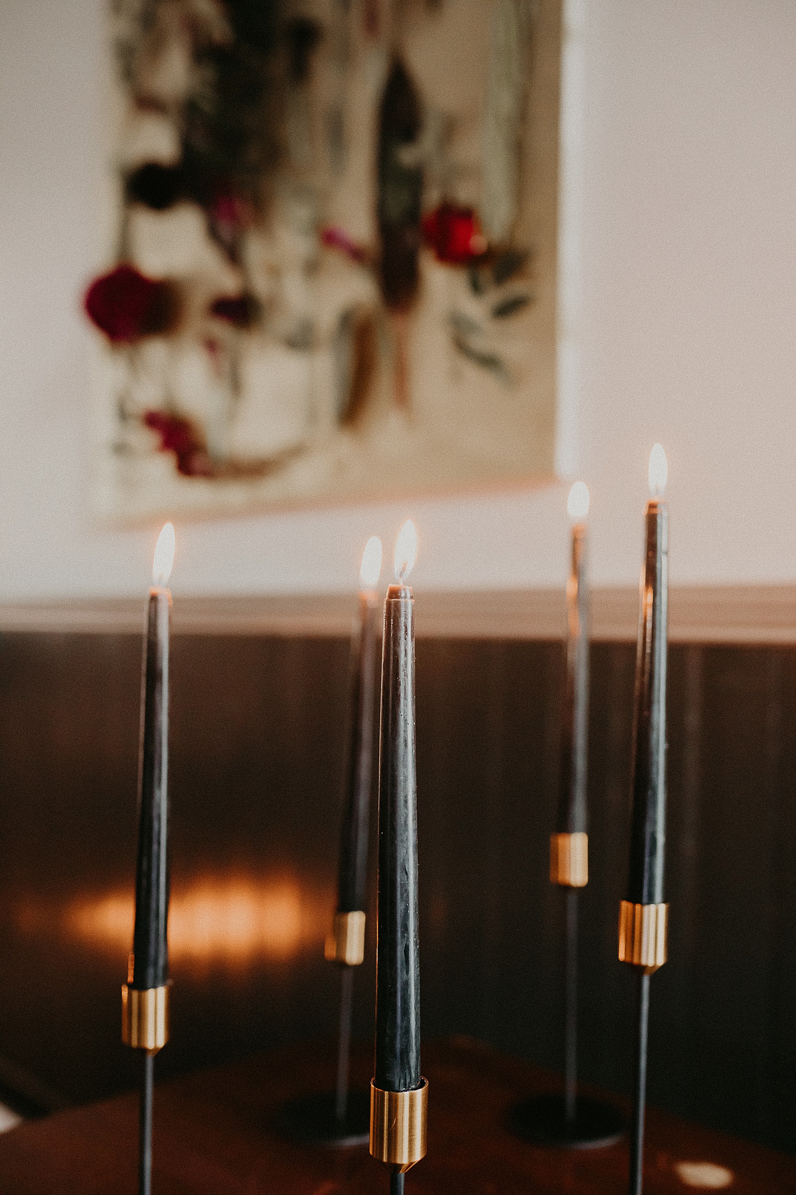 Black candles burning in the front of ceremony space with flower backdrop