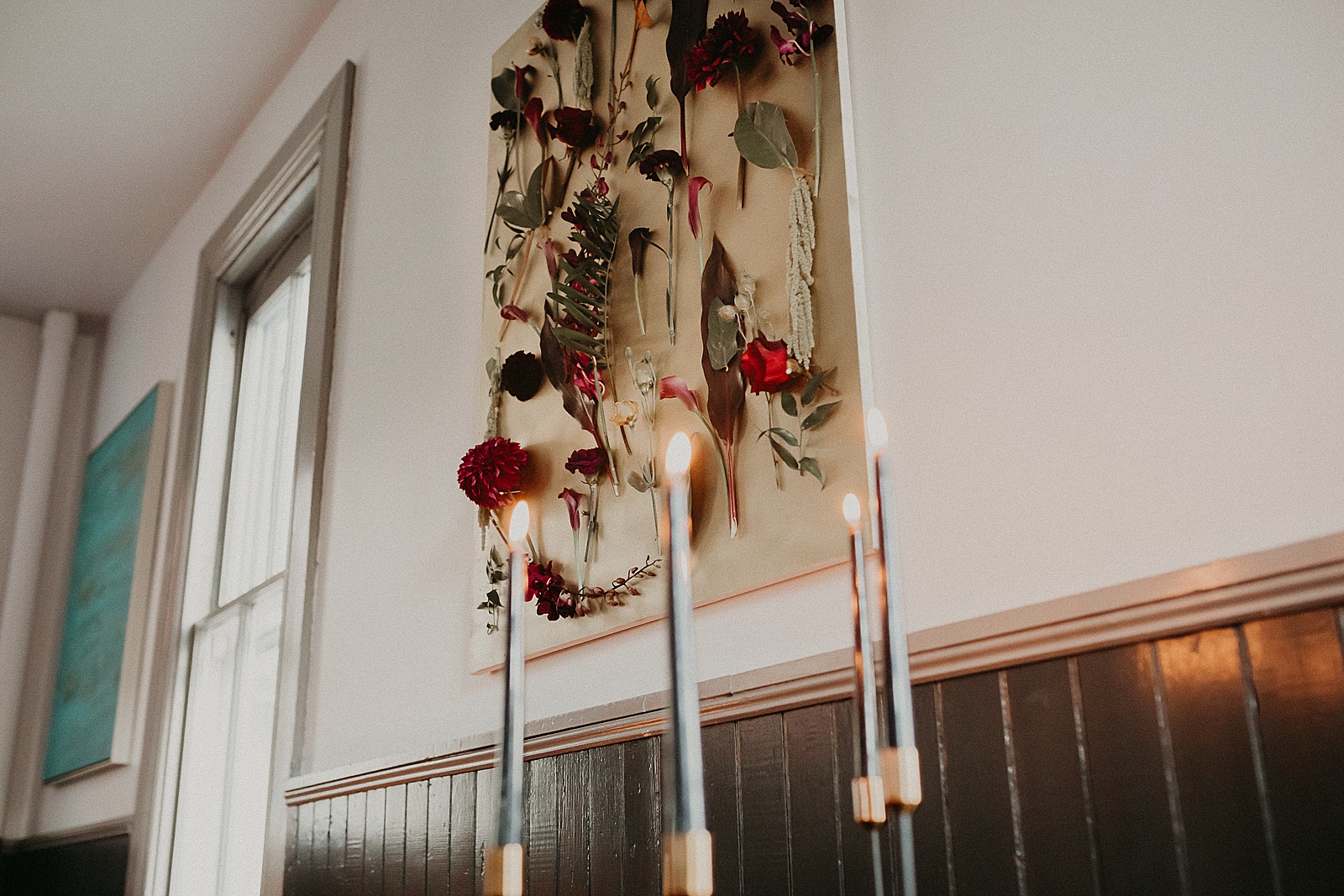 Black candles burning in the front of ceremony space with flower backdrop