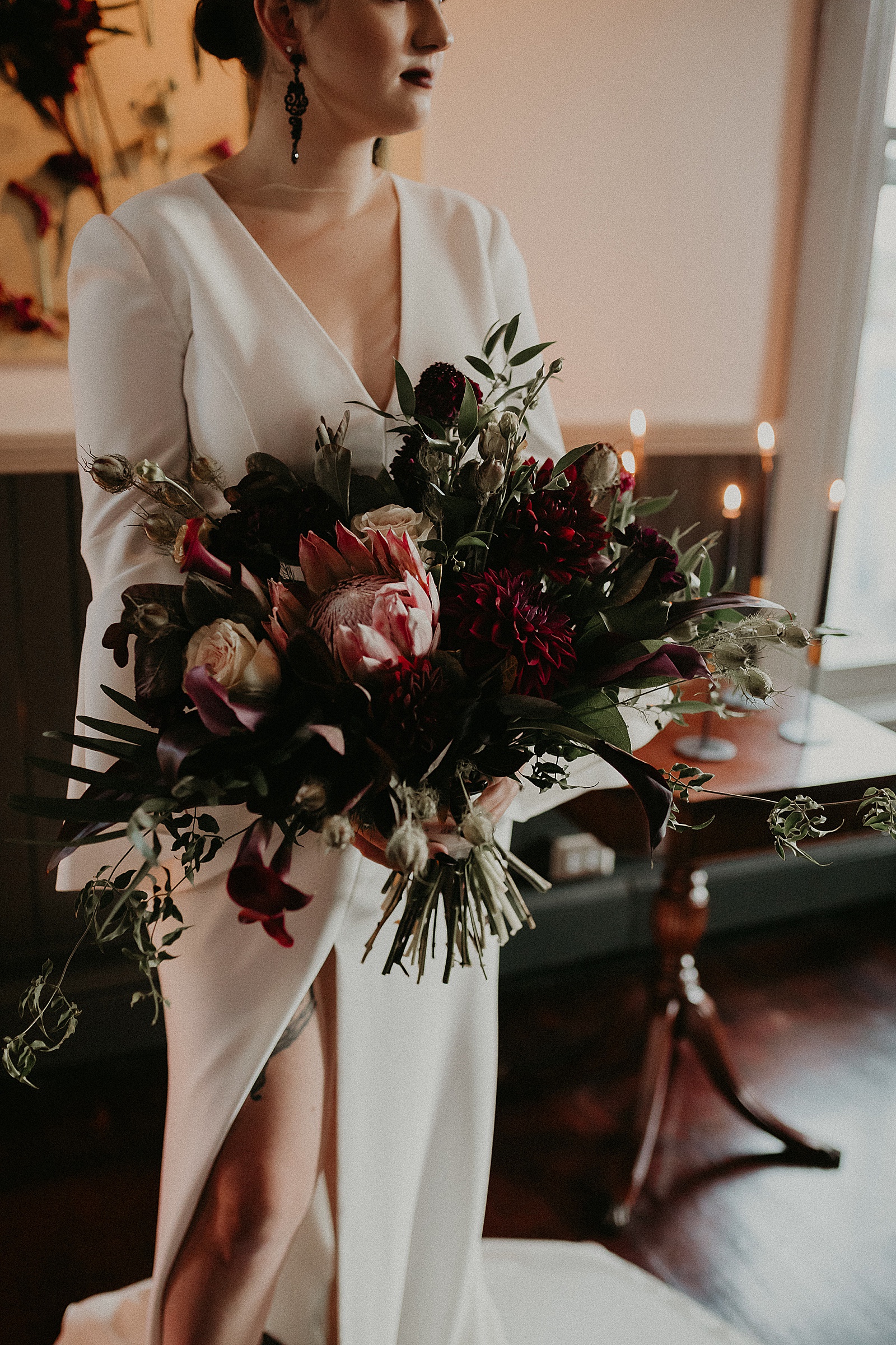 Dramatic dark and moody Bridal Portraits with oversized boho wedding bouquet in high slit wedding dress