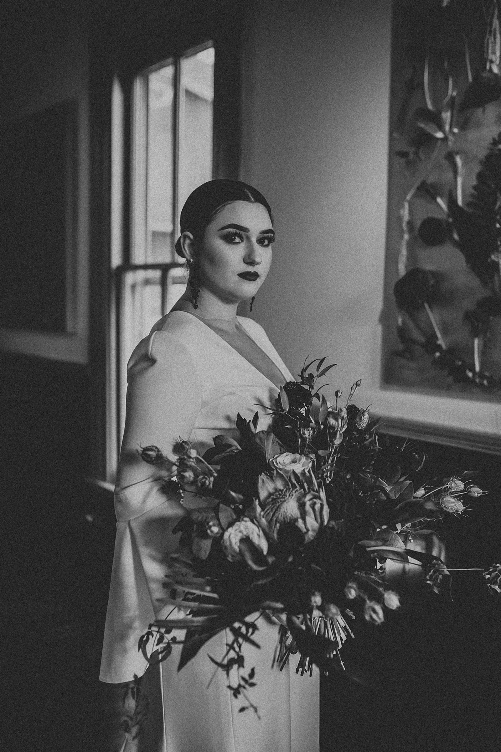 Dramatic dark and moody Bridal Portraits with oversized boho wedding bouquet in high slit wedding dress