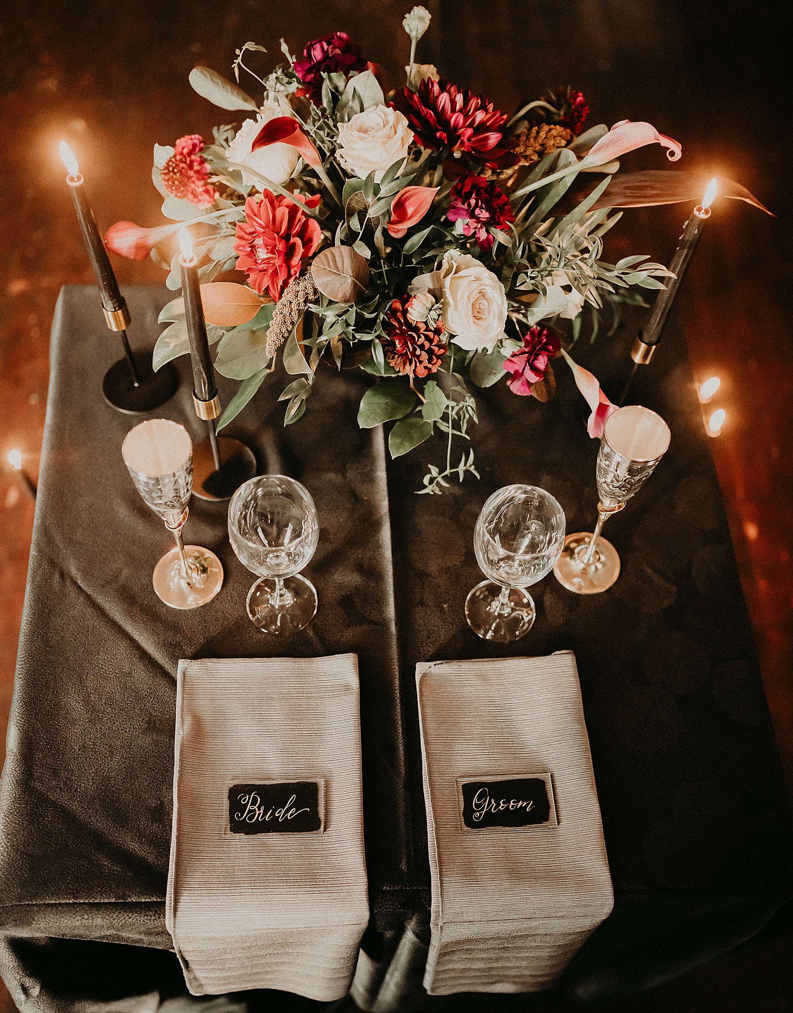 Sweetheart table with candles and dramatic bouquet placed in center