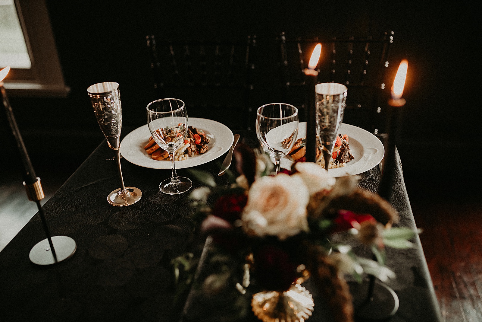 Sweetheart table with candles and dramatic bouquet placed in center