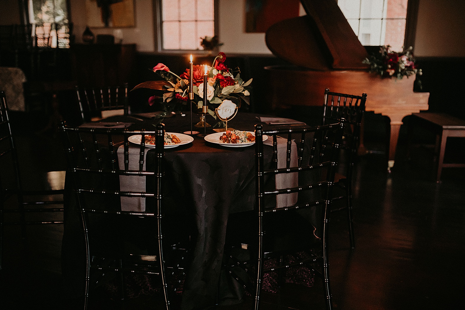 Candlelit reception table set with hand lettered place cards and a large floral centerpiece.