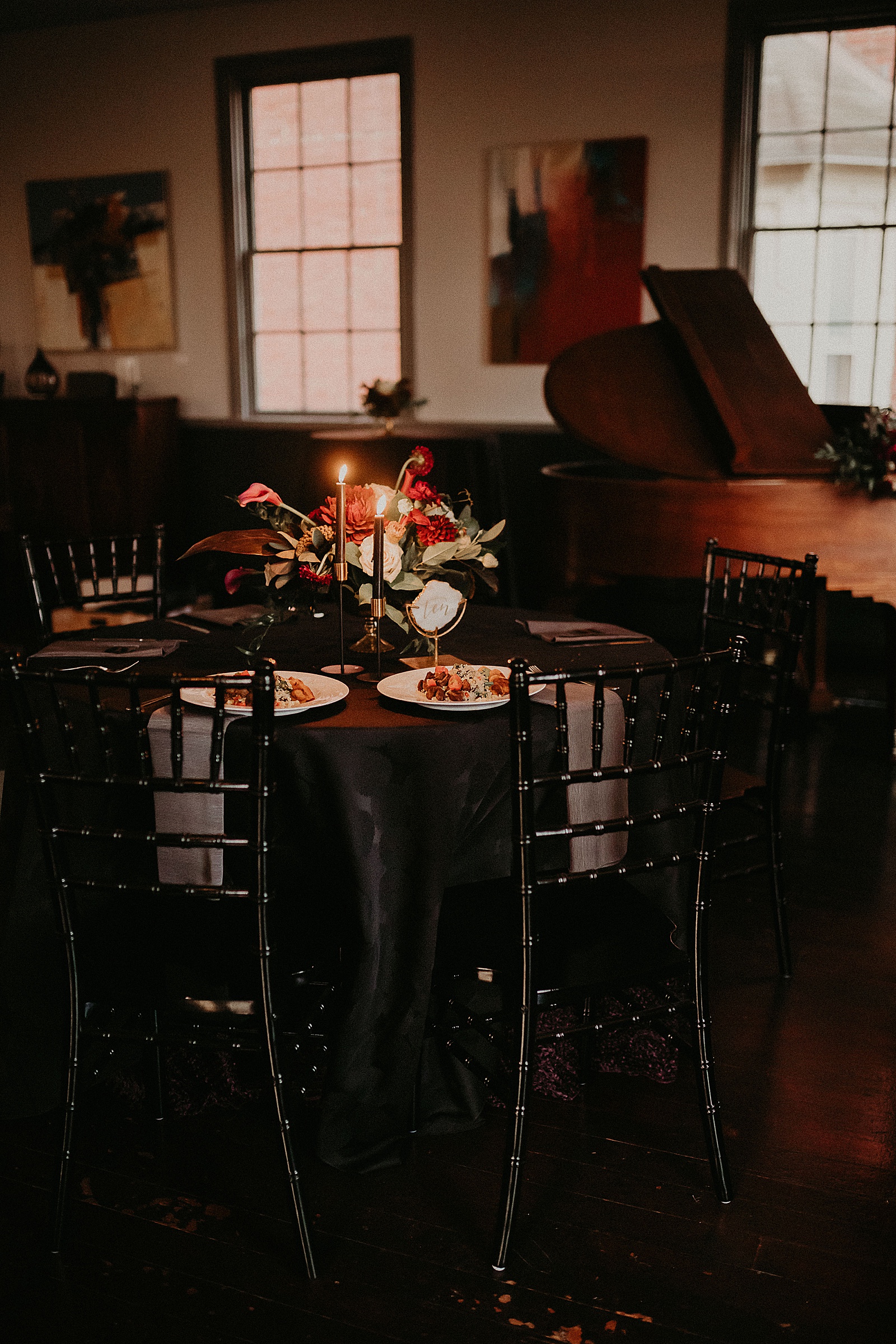 Candlelit reception table set with hand lettered place cards and a large floral centerpiece.