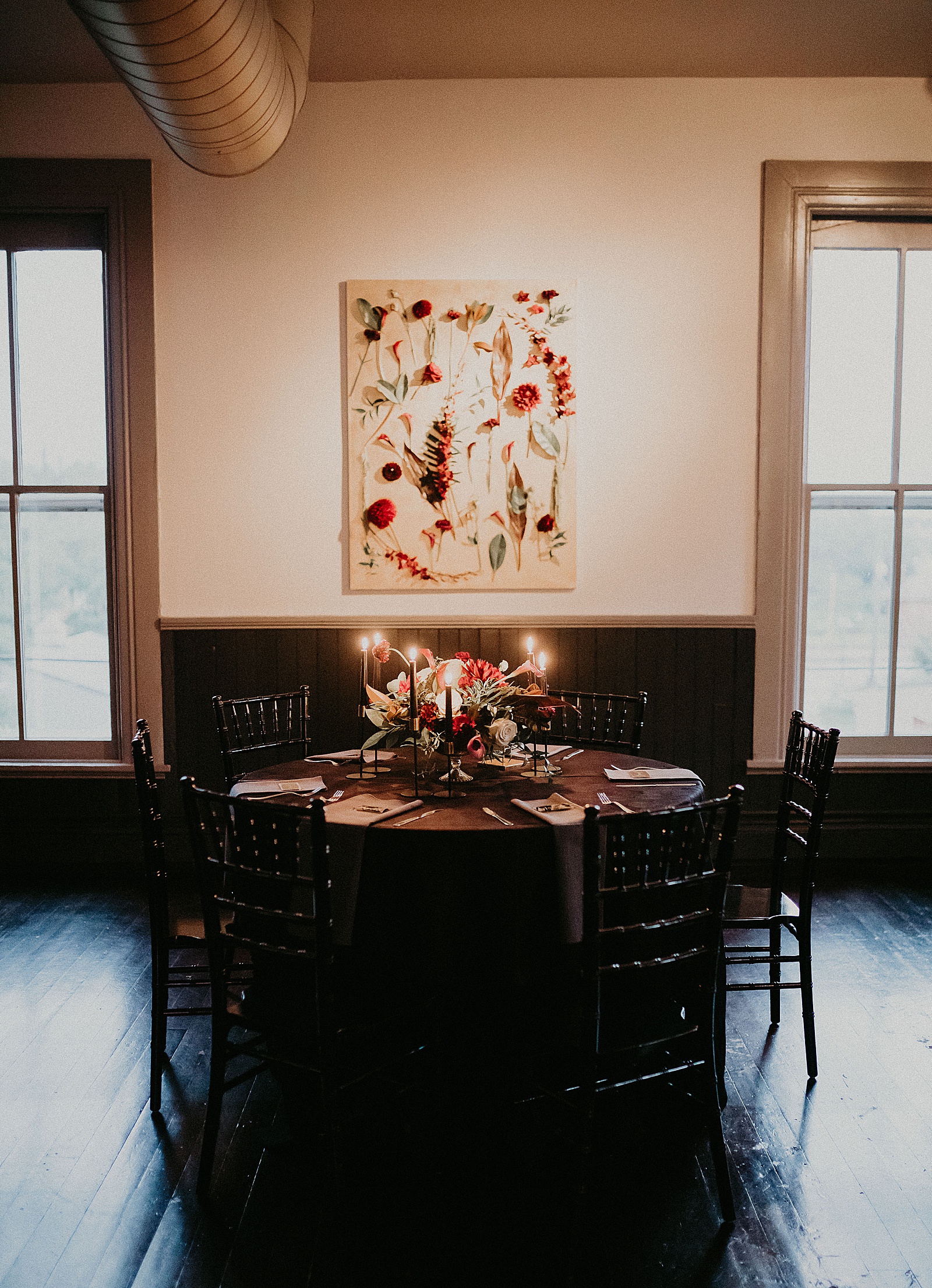 Candlelit reception table set with hand lettered place cards and a large floral centerpiece.