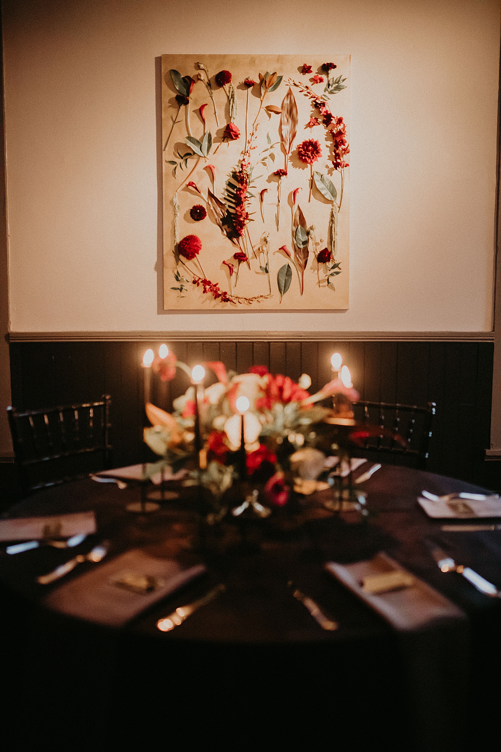Candlelit reception table set with hand lettered place cards and a large floral centerpiece.